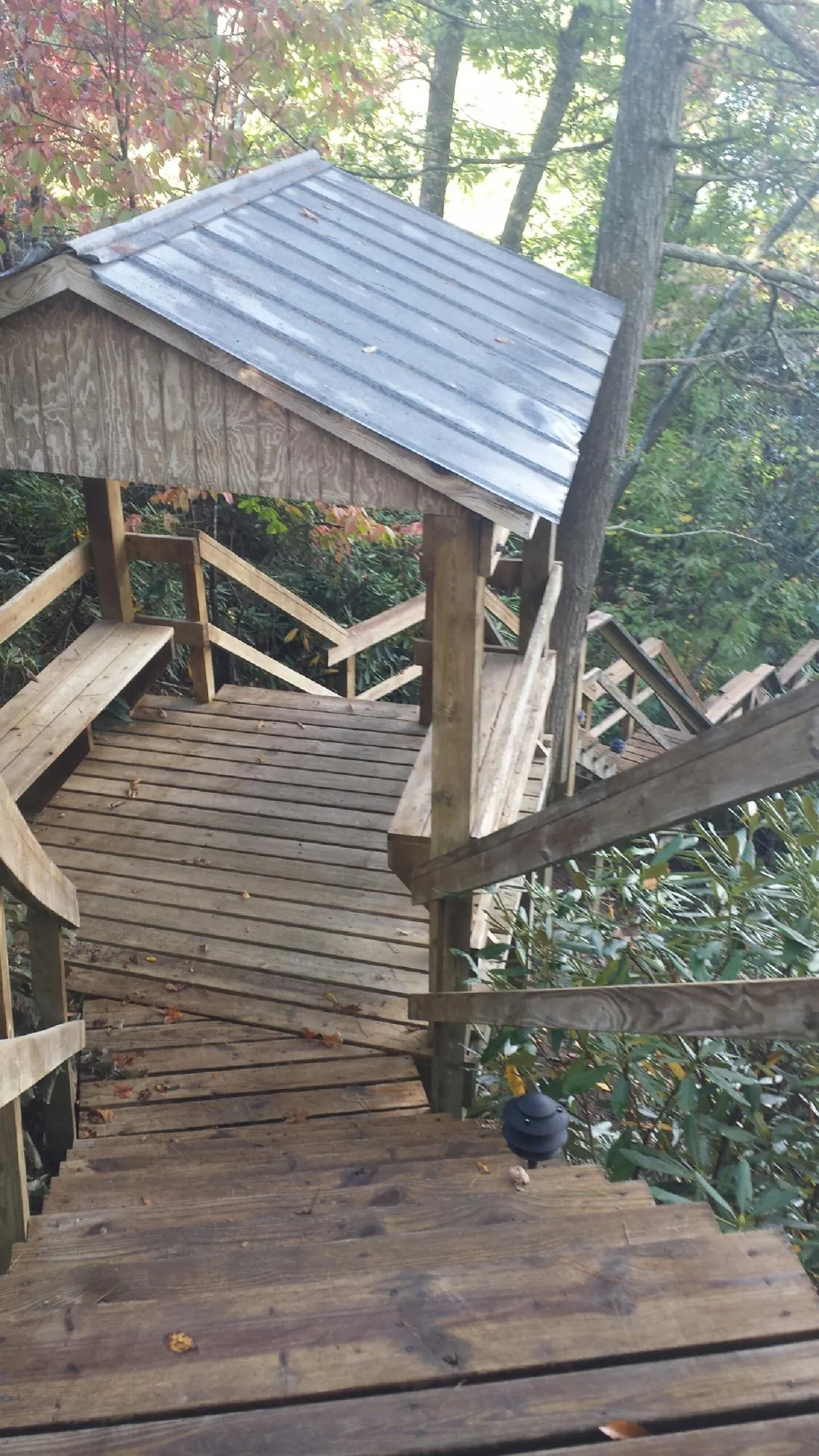 Metal roofed shelter over wooden steps on a wooded walkway — Skylight Repair & Installation work by our crew in Saint Joseph